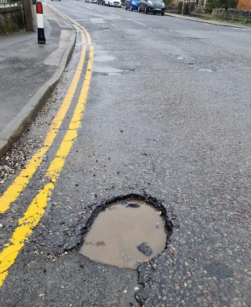 Large pothole with patched one further up the road
